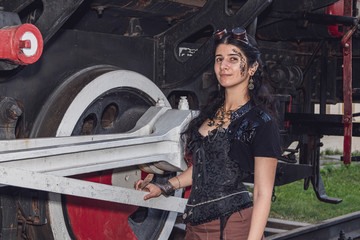 Fototapeta na wymiar Beautiful girl in steampunk clothes on the background of the train