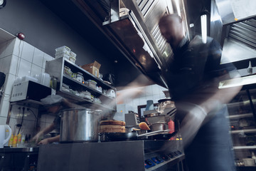 Behind the scenes of brands. The chef cooking in a professional kitchen of a restaurant meal for client or delivery. Open business from the inside. Meals during the quarantine. Hurrying up, motion.