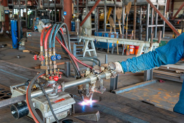 Using gas cutting machines to burning bending steel plates that is curled after welding for built-up h-beam at industrial factory.