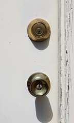 A close view of the door knob and the lock on the white wood door.