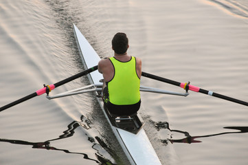 A rower, single sculler is paddling his rowing shell.