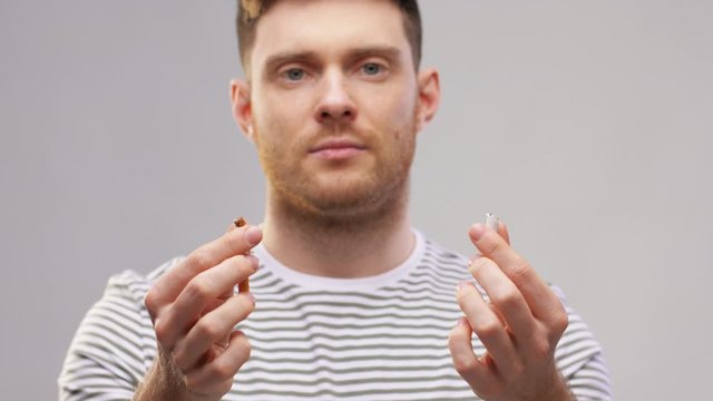 quit smoking and people concept - young man in striped t-shirt braking cigarette over grey background