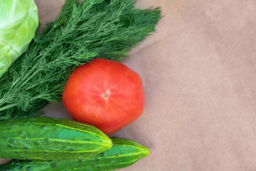 Eco-vegetables on a paper background close-up with a copy space. Tomatoes, cucumbers, dill top view. Soft focus.