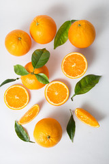 Bright juicy pieces and whole fruits with green leaves isolated on white background. Closeup, vertical shot, top view. Natural vitamin or organic food concept