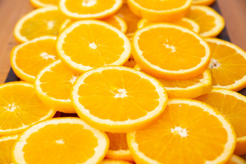 Close-up view of many orange slices laying on wooden desk. Bright summer citrus fruits. Side view. Studio shot. Nutrition and vegetarian concept