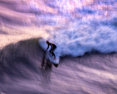 Surfing at sunset.  The pink clouds reflect onto the water as the surfer catches a wave in Los Angeles California. - Powered by Adobe