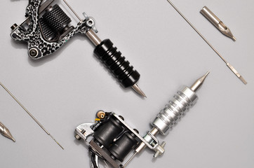 Tattoo machines, needles and all these tattoo stuff isolated on grey background. Tattoo guns. Pattern with tattoo machine, wallpaper for your business design