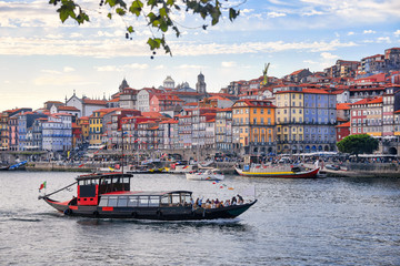 Porto, Portugal old town ribeira aerial promenade view with colorful houses, traditional facades, old multi-colored houses with red roof tiles, Douro river and boats. Aerial cityscape image of Porto