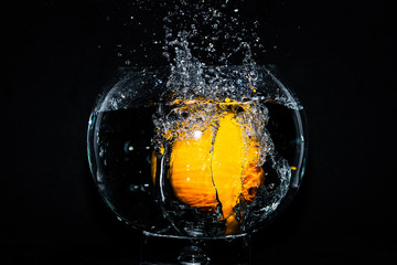 Orange splashing into a bowl of water