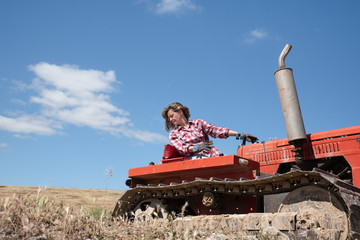 Farmer woman driving a tractor on her farm