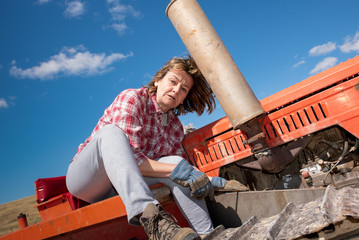 Woman mechanic repairing a tractor in the countryside