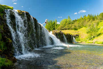 Fototapeta premium Dzieci skaczą z wodospadu i dobrze się bawią