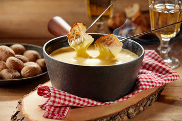 Steaming hot cheese fondue served with wine - obrazy, fototapety, plakaty