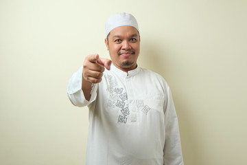 Portrait of young Asian muslim man pointing forward