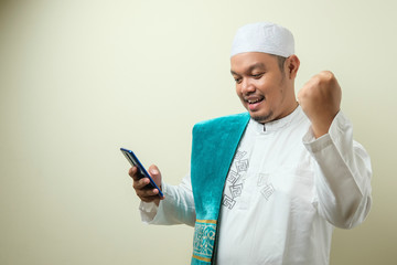 Fat Asian Muslim men looks surprised at the good news on phone