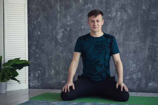 Sporty Elderly Guy Practicing Yoga Indoors. Senior Man Doing Stretching Exercise, Black Background. Active Lifestyle And Healthcare In Any Age, Copy Space