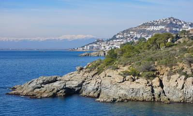 Spain Mediterranean sea coastline near Roses town on the Costa Brava with snow on the Pyrenees mountains in background, Girona province, Catalonia, Alt Emporda