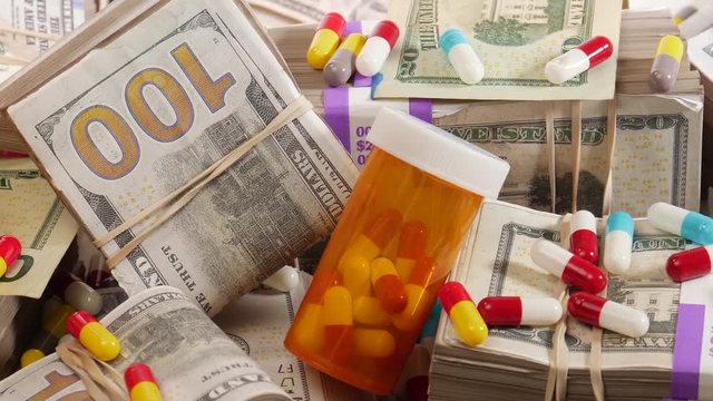 Containers with medication and various of pills around piles of USD American dollar bill cash. on the table