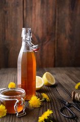 Homemade healthy dandelion syrup in a glass bottle, decorated with fresh flowers with copy space