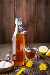 Homemade healthy dandelion syrup in a glass bottle, decorated with fresh flowers with copy space