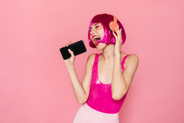 Image of excited pretty woman in headphone singing and using cellphone