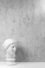 Mockup with ancient white statue of bust of Venus with grey textured background .Plaster sculpture...