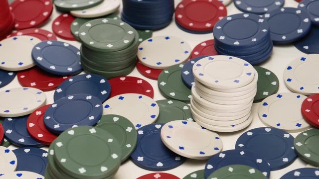 Piles of green, white and red pocker chips  on a white background rotating in circular mtion