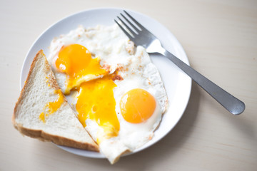 Two fried eggs with orange yolks, white toast in the morning for breakfast.