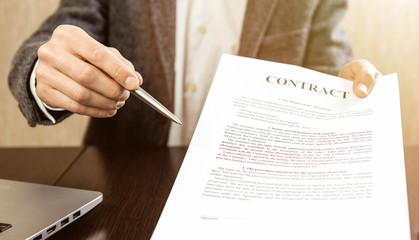 Businessman handing over a contract for signature offering a ballpoint pen in his hand