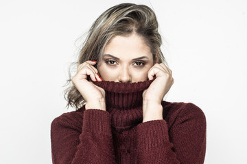 Young woman in turtleneck looking at camera. Attractive young blonde woman wearing maroon turtleneck and looking at camera isolated on white background. Beauty concept