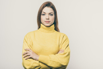 Obraz premium Confident young woman looking at camera. Portrait of beautiful serious young woman standing with crossed arms and looking at camera. Confidence concept