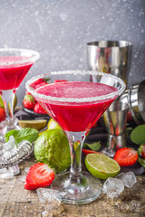 Summer cold alcohol drink. Strawberry margarita cocktail, with lime, mint and fresh strawberry on rustic wooden background