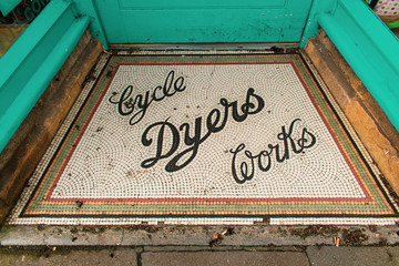 A beautiful colourful mosaic sign with the words Cyle Dyers Works on the front step of a shop in Sherborne, Dorset, United Kingdom.