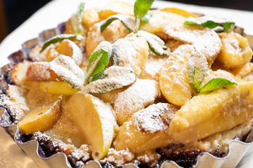 Juicy banana pie. Delicious Thanksgiving apple pie with mint or basil. Baking in the oven. Pie with banana. Sweet cupcake with baked fruit sprinkled with powder.