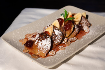 Juicy fritters with fruit for breakfast. Tasty cheesecakes with jam and bananas. Beautiful food from the restaurant cooked by a chef cook. Sweet dessert. A dish of flour and eggs.