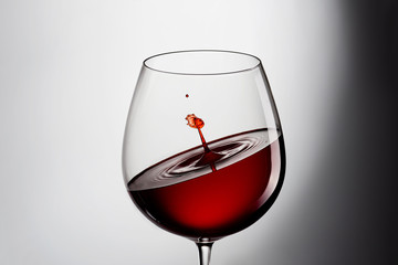 A glass of red wine with a splash