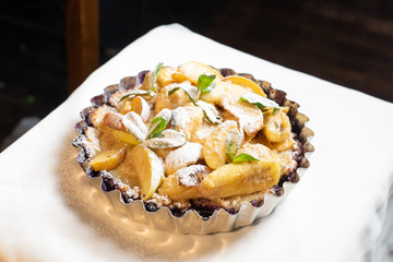 Juicy banana pie. Delicious Thanksgiving apple pie with mint or basil. Baking in the oven. Pie with banana. Sweet cupcake with baked fruit sprinkled with powder.
