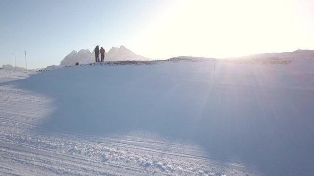 Aerial 4K - A revealing panoramic drone shot of 2 skiers standing on the edge of a mountain at the skislope/resort Portes Du Soleil (Avoriaz) in France on the border of Switzerland with his scenery.