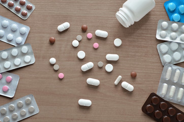 Pile various pills on a brown wooden table surface as a background close-up, top view. Concept of...