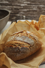 Freshly baked loaf of bread with flour covered crust unwrapped from baking paper