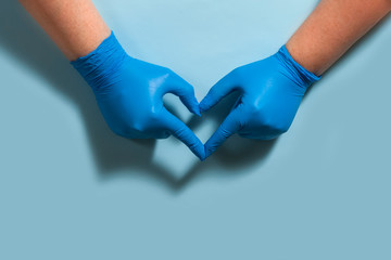 Heart, figure built of hands in blue rubber medical gloves on a light blue background.