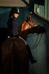 Young woman in special uniform and helmet riding horse. Equestrian sport - dressage.