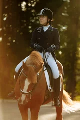 Foto op Canvas Young woman in special uniform and helmet riding horse. Equestrian sport - dressage. © matilda553