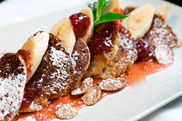 Juicy fritters with fruit for breakfast. Tasty cheesecakes with jam and bananas. Beautiful food from the restaurant cooked by a chef cook. Sweet dessert. A dish of flour and eggs.