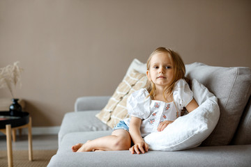 Little girl child sitting on a sofa. Close-up portrait of a baby girl