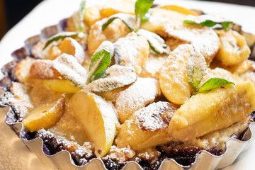 Juicy banana pie. Delicious Thanksgiving apple pie with mint or basil. Baking in the oven. Pie with banana. Sweet cupcake with baked fruit sprinkled with powder.
