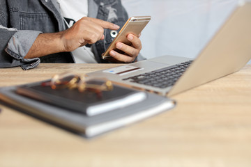 Man hands in grey jean sitting and looking credit card and using laptop computer on table for online payment or shopping online. Business man using mobile phone while sitting. E-Banking concept