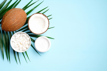 Coconut oil cosmetic body cream on blue background with palm leaf. Flat lay, top view. SPA natural organic product, skincare concept