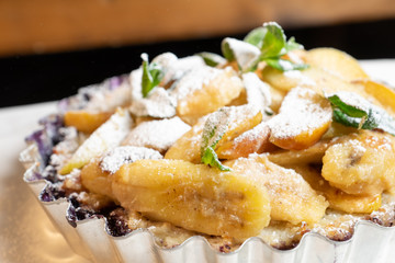 Juicy banana pie. Delicious Thanksgiving apple pie with mint or basil. Baking in the oven. Pie with banana. Sweet cupcake with baked fruit sprinkled with powder.