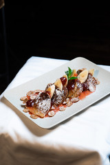 Juicy fritters with fruit for breakfast. Tasty cheesecakes with jam and bananas. Beautiful food from the restaurant cooked by a chef cook. Sweet dessert. A dish of flour and eggs.